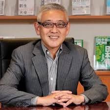 机の前で微笑む案内人の写真